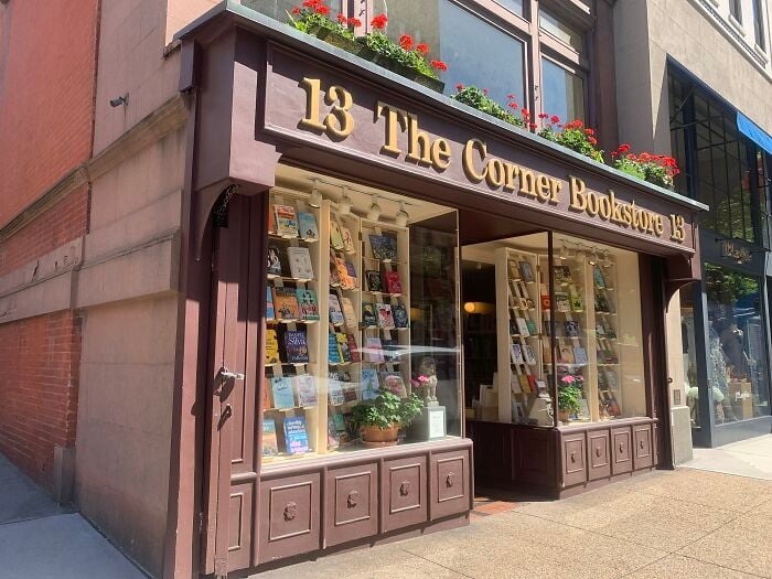 Exterior encantador de livraria com floreiras, mostrando uma livraria acolhedora e m&aacute;gica de todo o mundo.